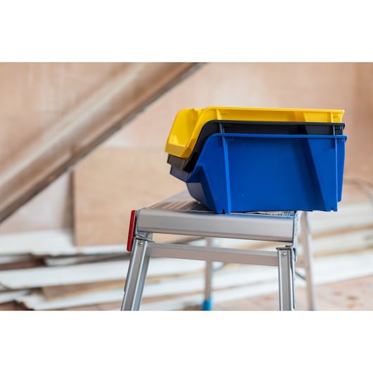 STANLEY STST82743-1 stackable yellow and blue storage bins on a metal step ladder side view.