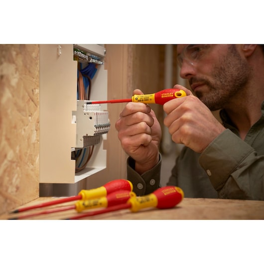 Photo of Stanley XTHT0-62692 insulated screwdriver in use on electrical panel, with two others on table.