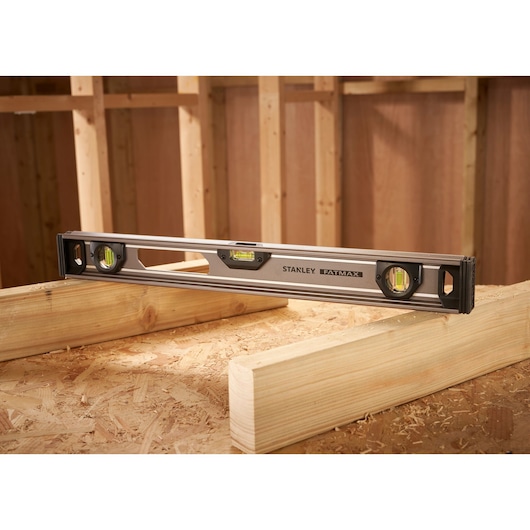 STANLEY XTHT1-42131 spirit level on wood beams in construction setting, side angle.